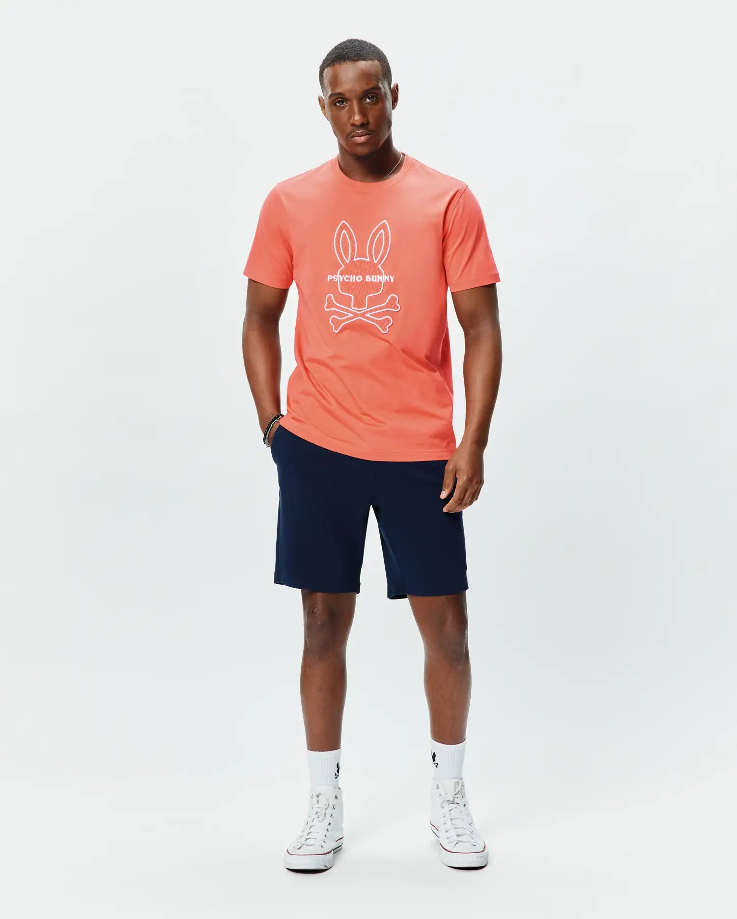 Mens Craig Graphic Tee in coral, featuring a classic fit and soft jersey fabric, with a large white Psycho Bunny skull and crossbones logo and text prominently displayed on the center chest. (4)