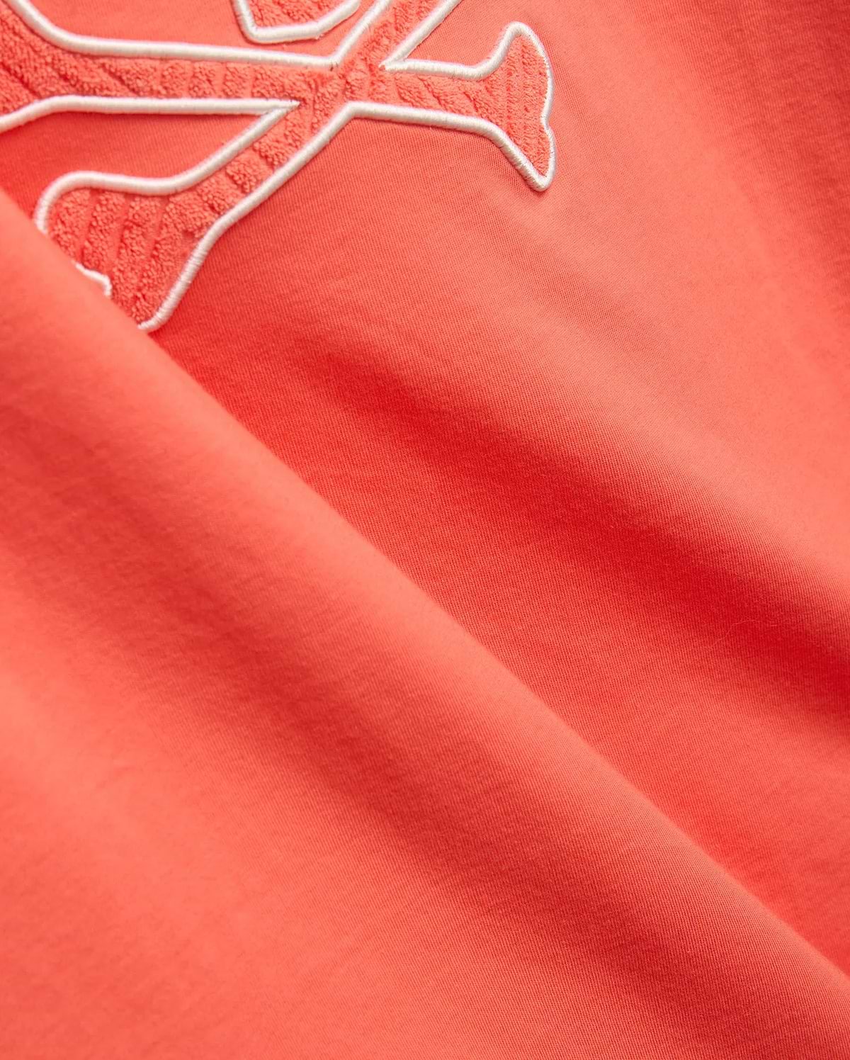 Mens Craig Graphic Tee in coral, made from soft jersey knit, featuring a large embroidered Psycho Bunny skull logo with a white outline and textured coral fill. (2)