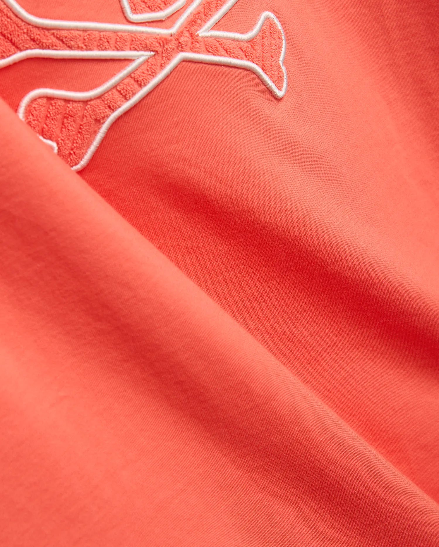 Mens Craig Graphic Tee in coral, made from soft jersey knit, featuring a large embroidered Psycho Bunny skull logo with a white outline and textured coral fill. (2)