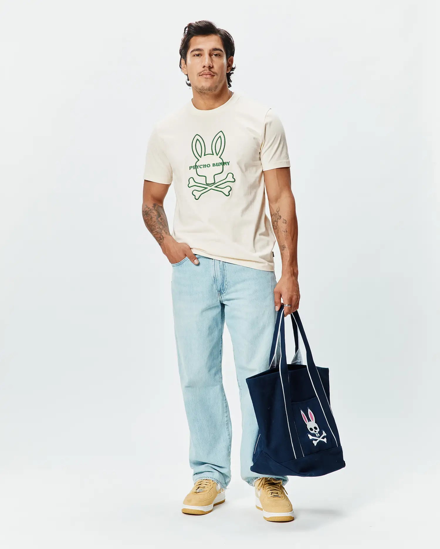 Mens Craig Graphic Tee, a classic fit cream soft jersey crew neck t-shirt featuring a large green outline Psycho Bunny skull and crossbones logo with text on the center chest. (2)