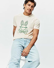 Mens Craig Graphic Tee, a classic fit cream jersey t-shirt with a prominent green outline graphic of the iconic Psycho Bunny skull and crossbones logo and text centered on the chest. (4)
