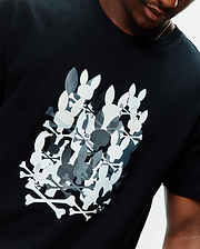 Black Mens Tanner Graphic Tee, classic fit, soft jersey knit, featuring a large chest graphic of overlapping white, grey, and dark grey Psycho Bunny skull and crossbones logos.