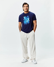 Mens Tanner Graphic Tee, a navy blue classic fit jersey t-shirt featuring a large central graphic print of multiple blue Psycho Bunny skull and crossbones logos.