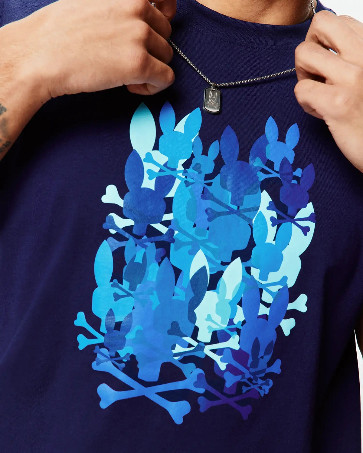 Classic fit Mens Tanner Graphic Tee in navy blue jersey, featuring a bold chest print of overlapping Psycho Bunny skull and crossbones in light to dark blue hues.