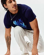 Mens Tanner Graphic Tee, a classic fit navy blue jersey t-shirt with a large chest graphic of multiple bunny skulls in teal, light blue, and darker blue. Paired with light beige textured drawstring pants.