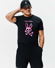 Black jersey Mens Adler Graphic Tee with a large pink Psycho Bunny skull and crossbones graphic on the chest, paired with black textured shorts and a black cap with a white bunny logo. (4)