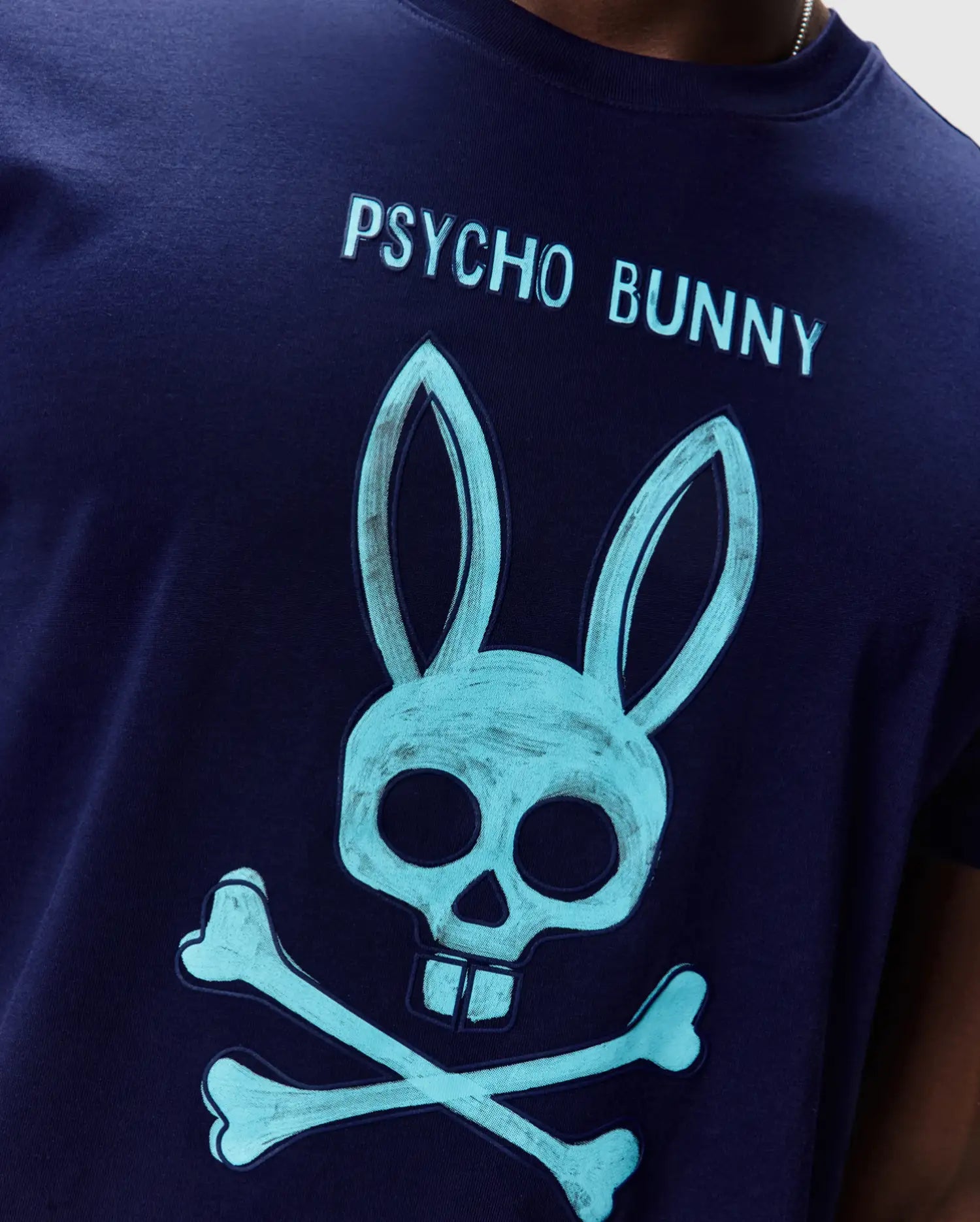 Mens Adler Graphic Tee, navy jersey t-shirt with a large teal Psycho Bunny skull and crossbones graphic on the chest, featuring Psycho Bunny text above. (3)