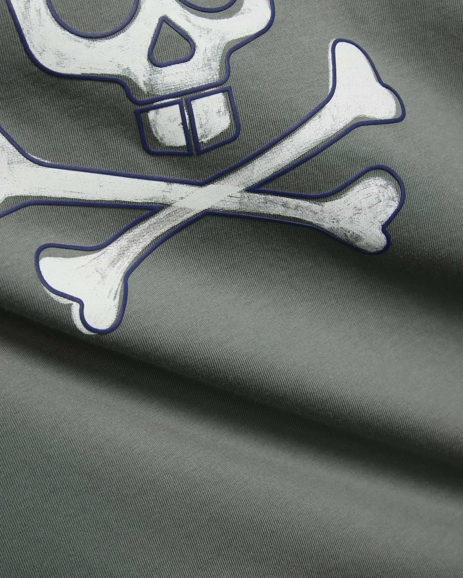 Mens Adler Graphic Tee in dark sage green, soft jersey knit fabric, showcasing a large, distressed white Psycho Bunny skull and crossbones graphic with a bold dark blue outline.