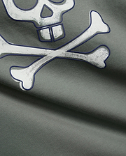 Mens Adler Graphic Tee in dark sage green, soft jersey knit fabric, showcasing a large, distressed white Psycho Bunny skull and crossbones graphic with a bold dark blue outline.