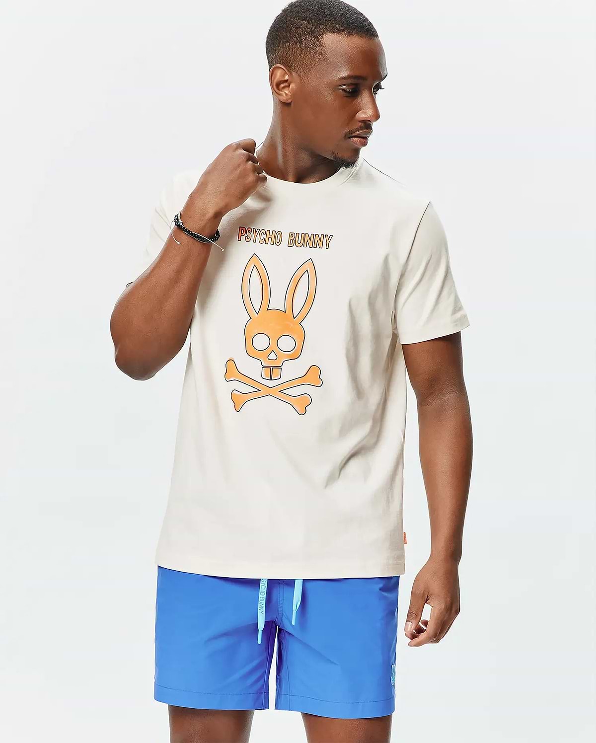 Mens Adler Graphic Tee, cream smooth jersey knit, classic fit, featuring a large orange Psycho Bunny skull logo graphic on the chest with orange PSYCHO BUNNY text above. (4)