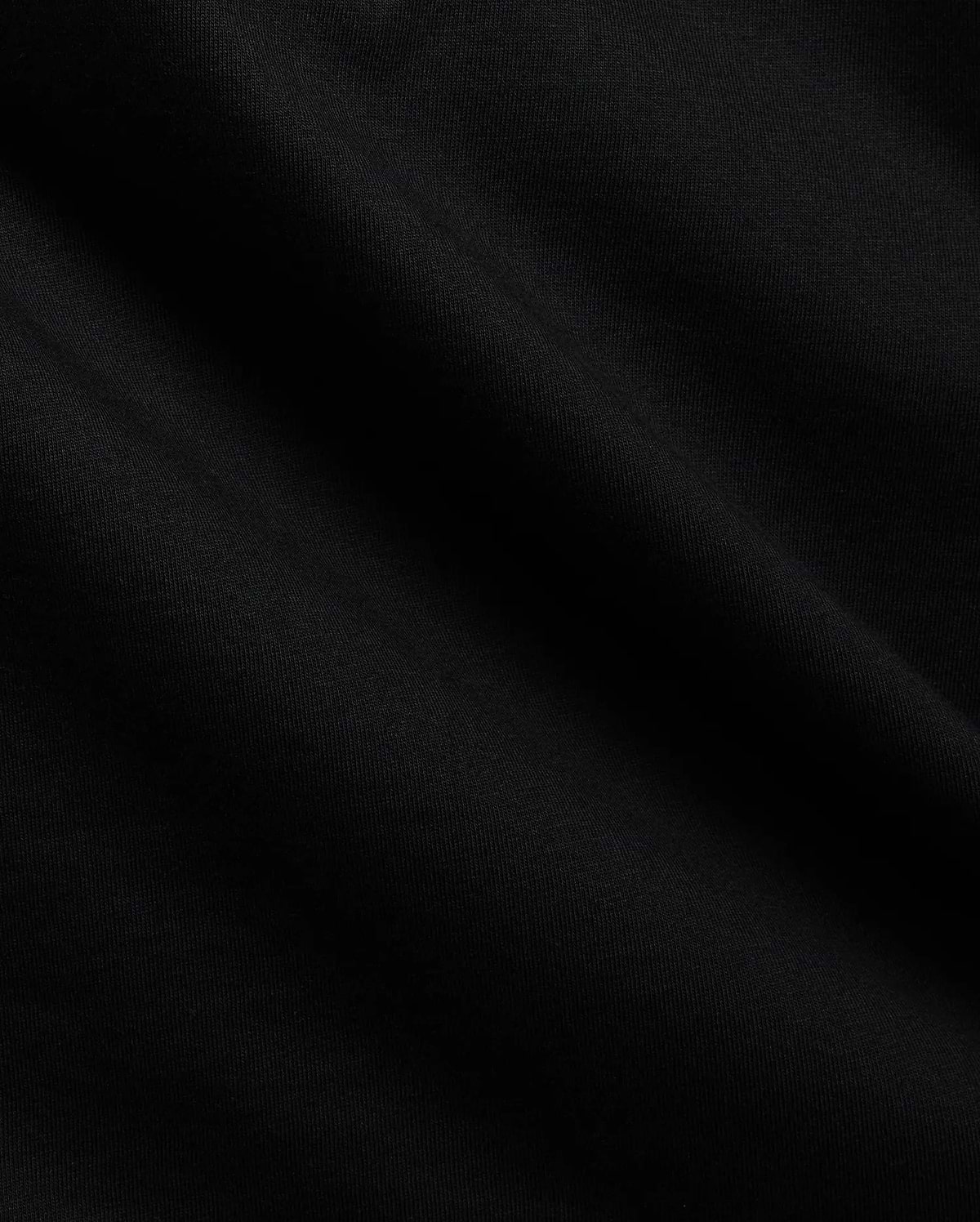 Close-up of the Mens Tobias Graphic Tee in deep black, highlighting its premium, soft cotton jersey knit fabric with subtle, flowing folds and a refined, smooth texture.