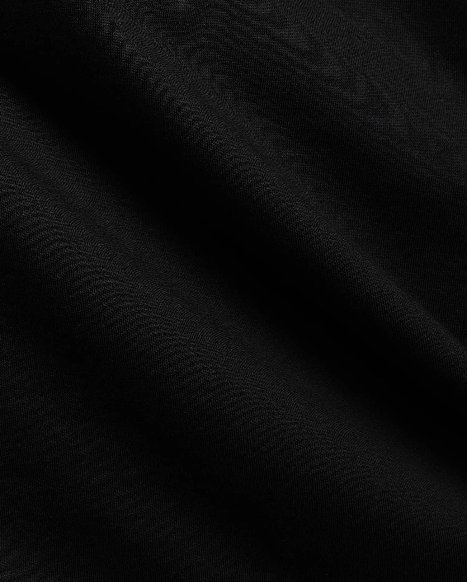 Close-up of the Mens Tobias Graphic Tee in deep black, highlighting its premium, soft cotton jersey knit fabric with subtle, flowing folds and a refined, smooth texture.