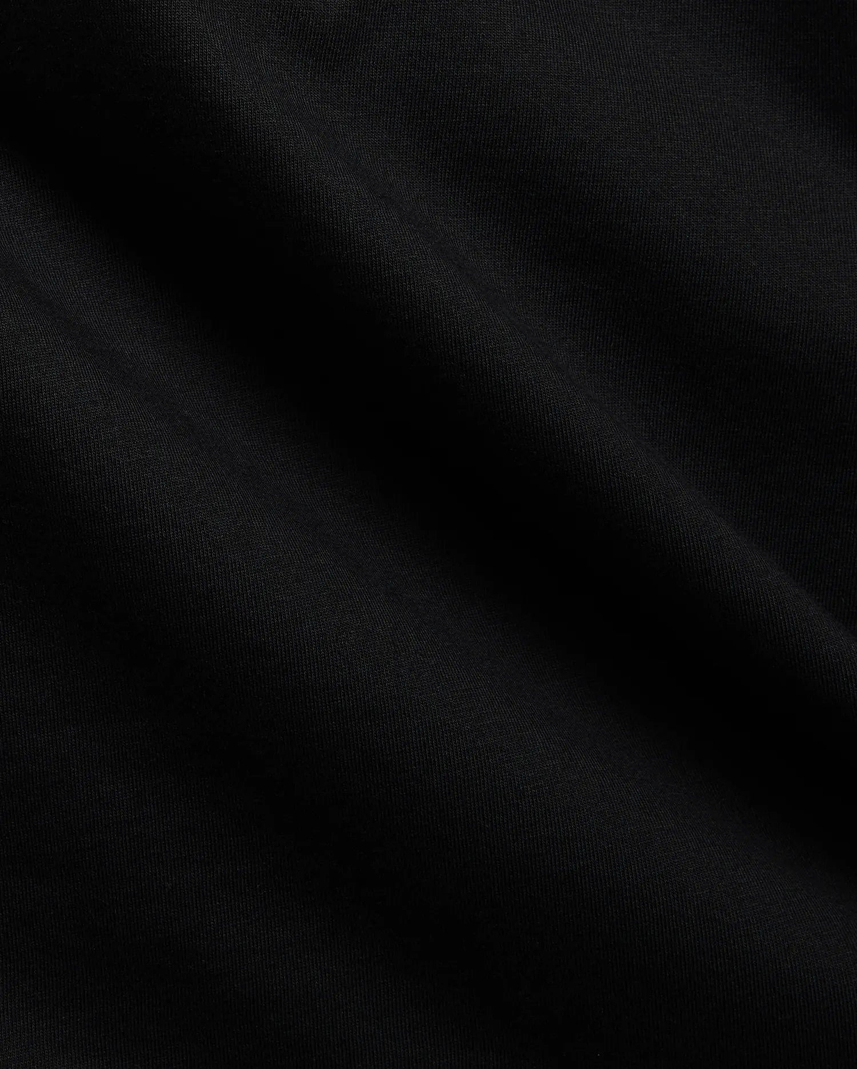 Close-up of the Mens Tobias Graphic Tee in deep black, highlighting its premium, soft cotton jersey knit fabric with subtle, flowing folds and a refined, smooth texture.