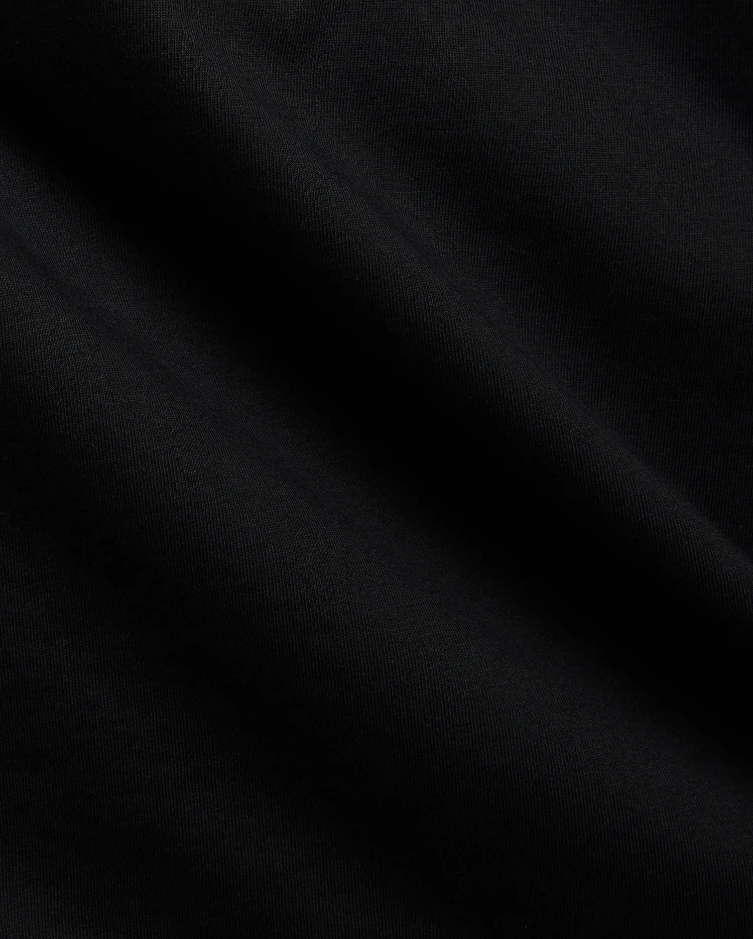Close-up of the Mens Tobias Graphic Tee in deep black, highlighting its premium, soft cotton jersey knit fabric with subtle, flowing folds and a refined, smooth texture.