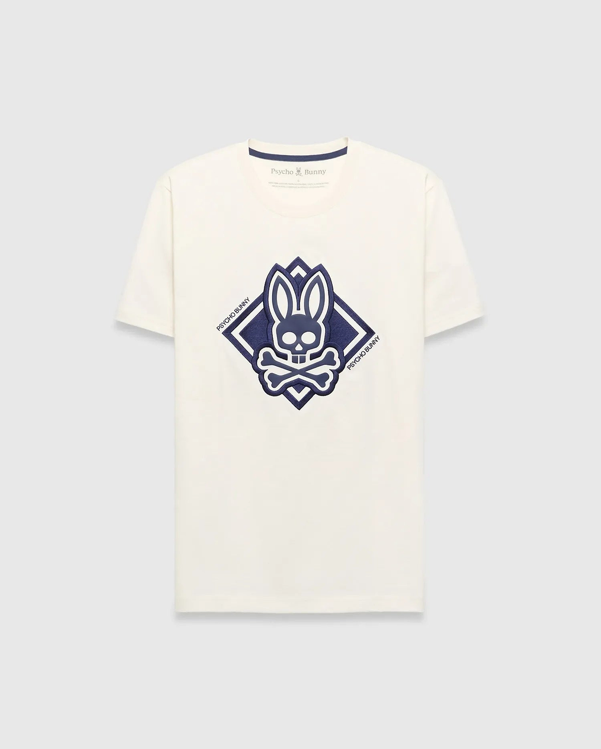 Mens Tobias Graphic Tee, a cream classic fit jersey t-shirt with a large central navy blue Psycho Bunny skull and crossbones logo inside a diamond graphic, featuring Psycho Bunny text.