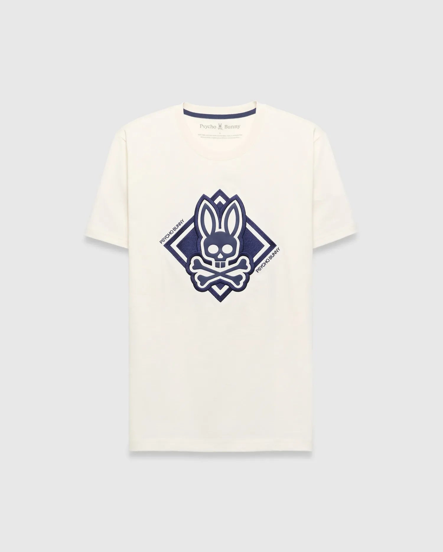 Mens Tobias Graphic Tee, a cream classic fit jersey t-shirt with a large central navy blue Psycho Bunny skull and crossbones logo inside a diamond graphic, featuring Psycho Bunny text.