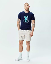 Mens Ethan Graphic Tee in navy blue jersey, featuring a large, classic fit, light blue faceted Psycho Bunny skull logo on the chest, paired with classic beige shorts. (6)