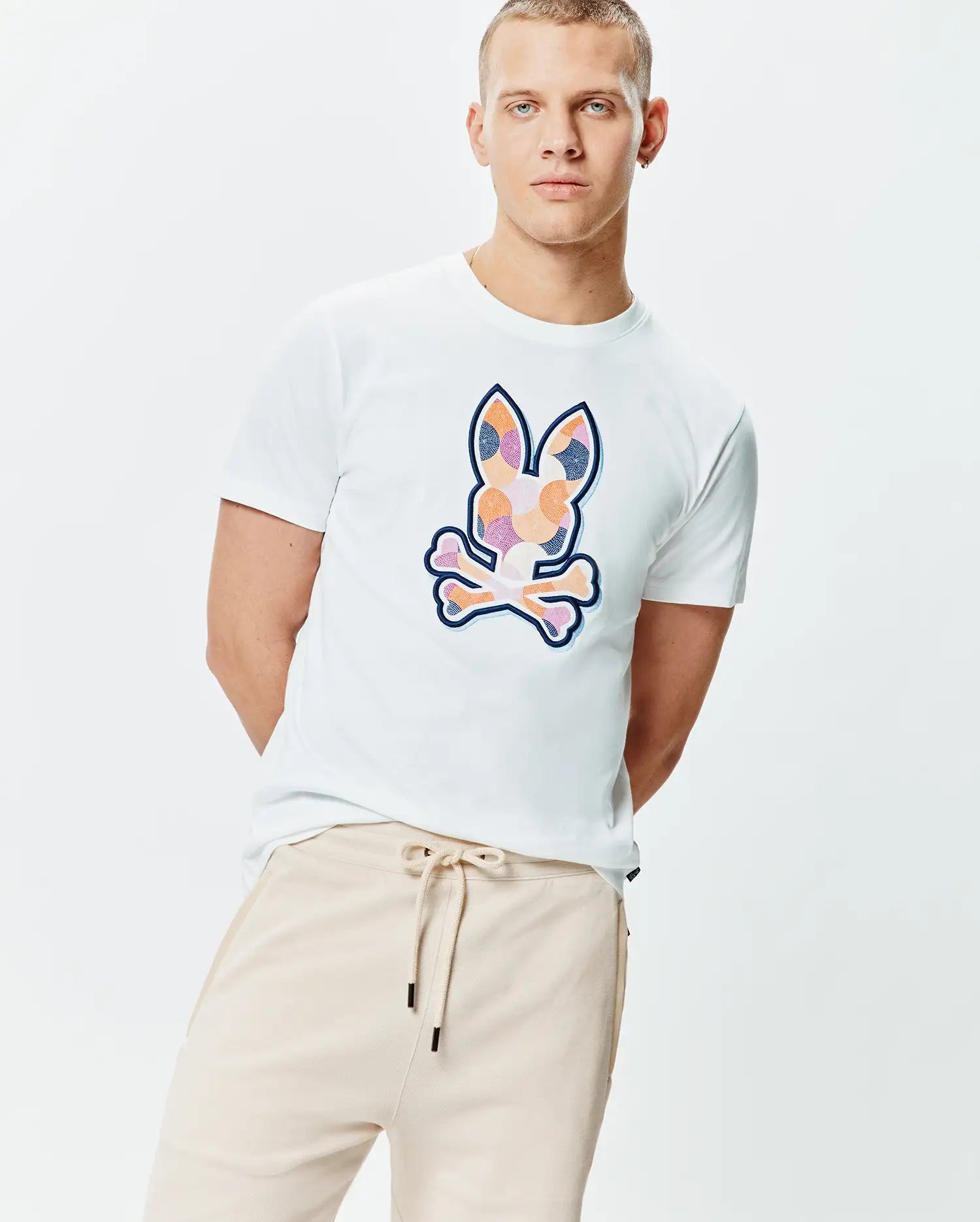 White Mens Ethan Graphic Tee, classic fit, smooth jersey knit, featuring a large, vibrant multi-color mosaic Psycho Bunny skull logo with a dark blue outline centered on the chest. (2)