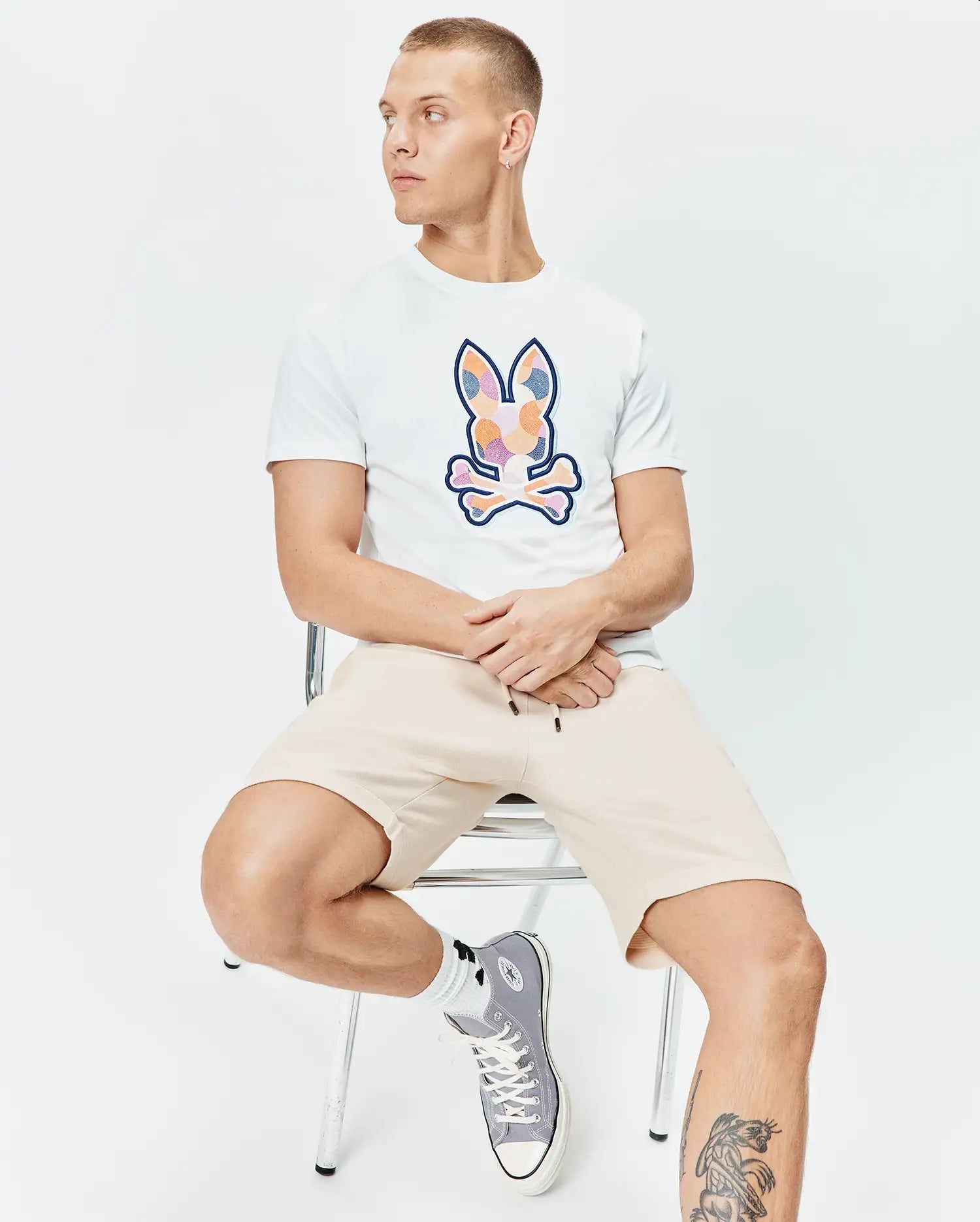 Mens Ethan Graphic Tee, white classic fit jersey with a large colorful mosaic Psycho Bunny skull logo on the chest, paired with relaxed fit beige knit drawstring shorts. (4)