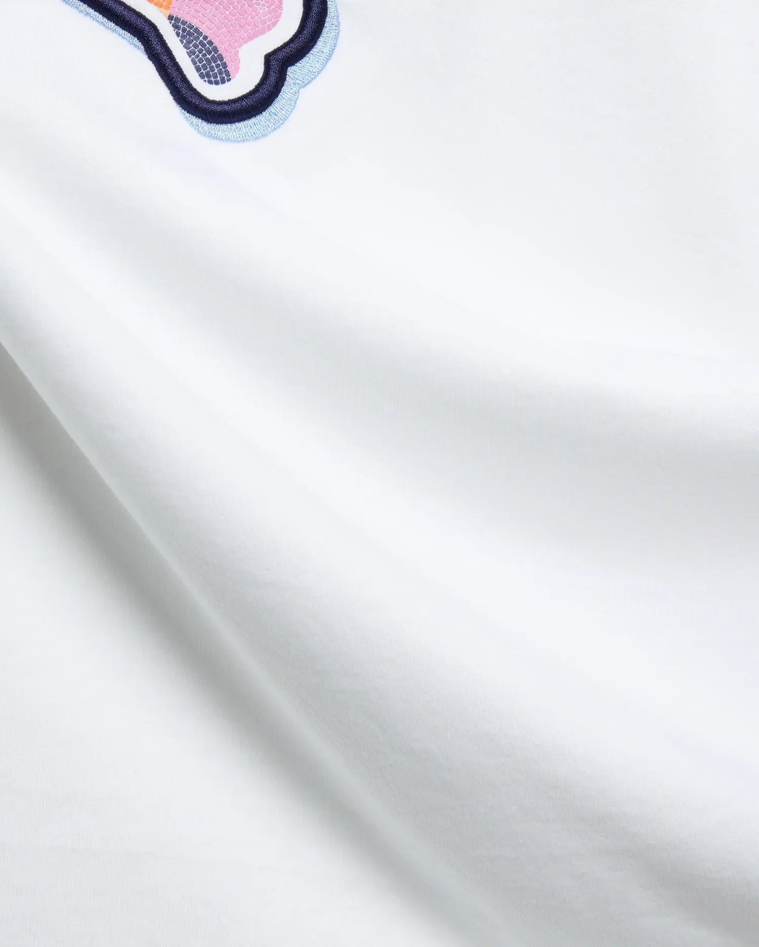 White Mens Ethan Graphic Tee, classic fit jersey, featuring a large embroidered Psycho Bunny skull logo with dark blue, light blue, pink, and orange mosaic details. (6)