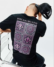 Mens Frank Back Graphic Tee, black classic fit jersey t-shirt with a large back graphic featuring pink and purple mosaic patterns, mandalas, and small Psycho Bunny skull logos, topped with pink PSYCHO BUNNY text.