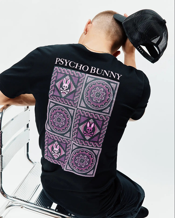 Mens Frank Back Graphic Tee, black classic fit jersey t-shirt with a large back graphic featuring pink and purple mosaic patterns, mandalas, and small Psycho Bunny skull logos, topped with pink PSYCHO BUNNY text.