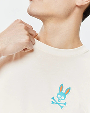 Cream Mens Frank Back Graphic Tee, classic fit, smooth jersey knit, featuring a small embroidered blue and orange Psycho Bunny skull and crossbones logo on the left chest.