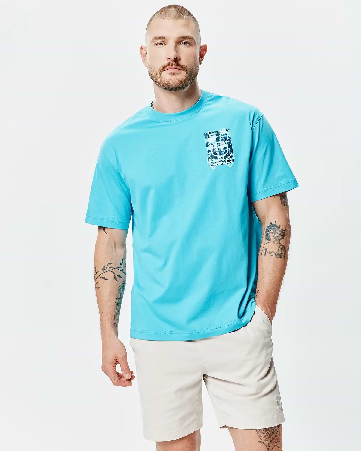 Mens Isaac Relaxed Fit Tee in vibrant aqua blue, a relaxed fit jersey t-shirt with a small, distressed blue and white Psycho Bunny skull graphic print on the left chest.