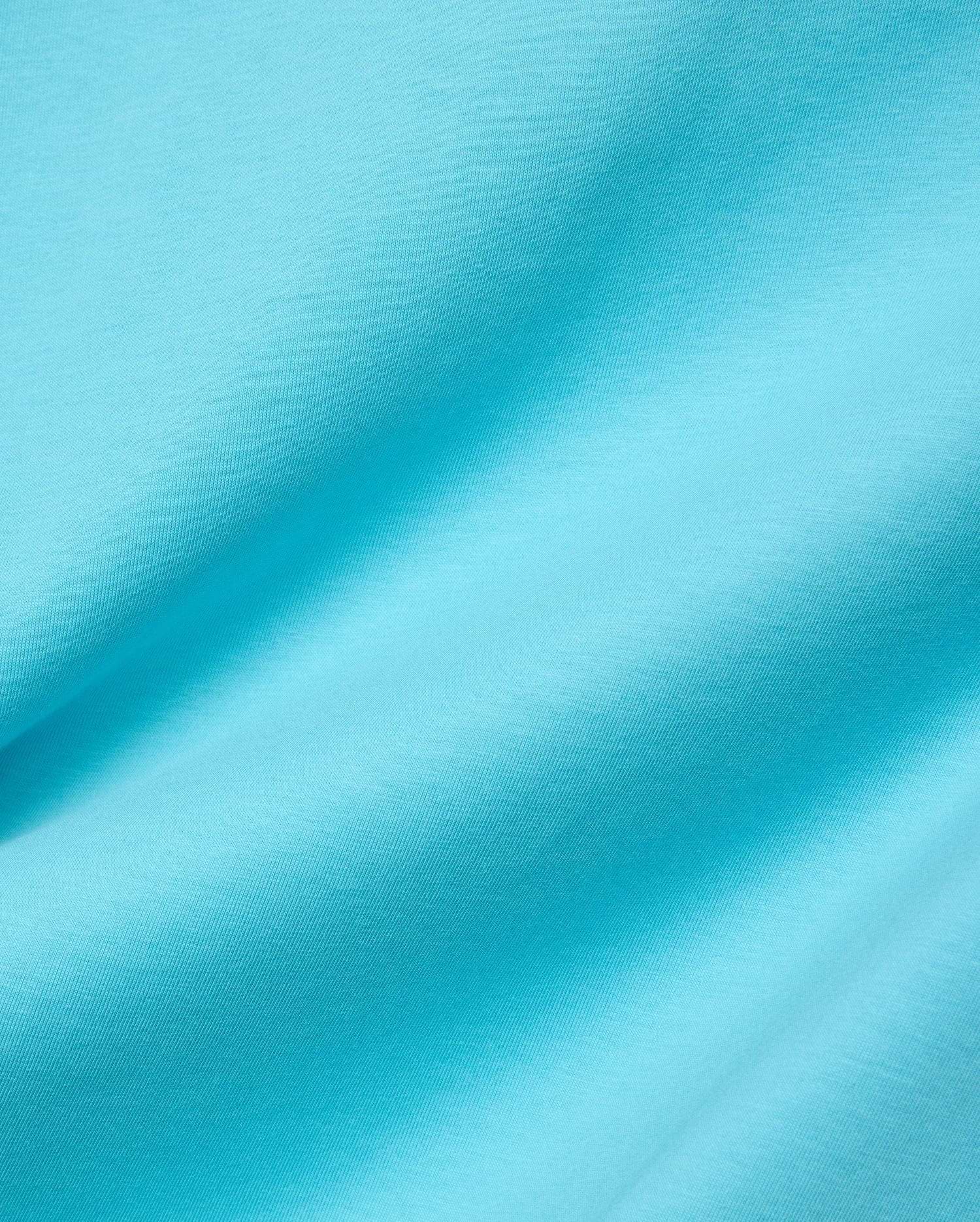 Mens Isaac Relaxed Fit Tee in bright aqua blue, soft jersey knit fabric with visible subtle texture and gentle folds, featuring the iconic small embroidered Psycho Bunny skull logo on the chest.