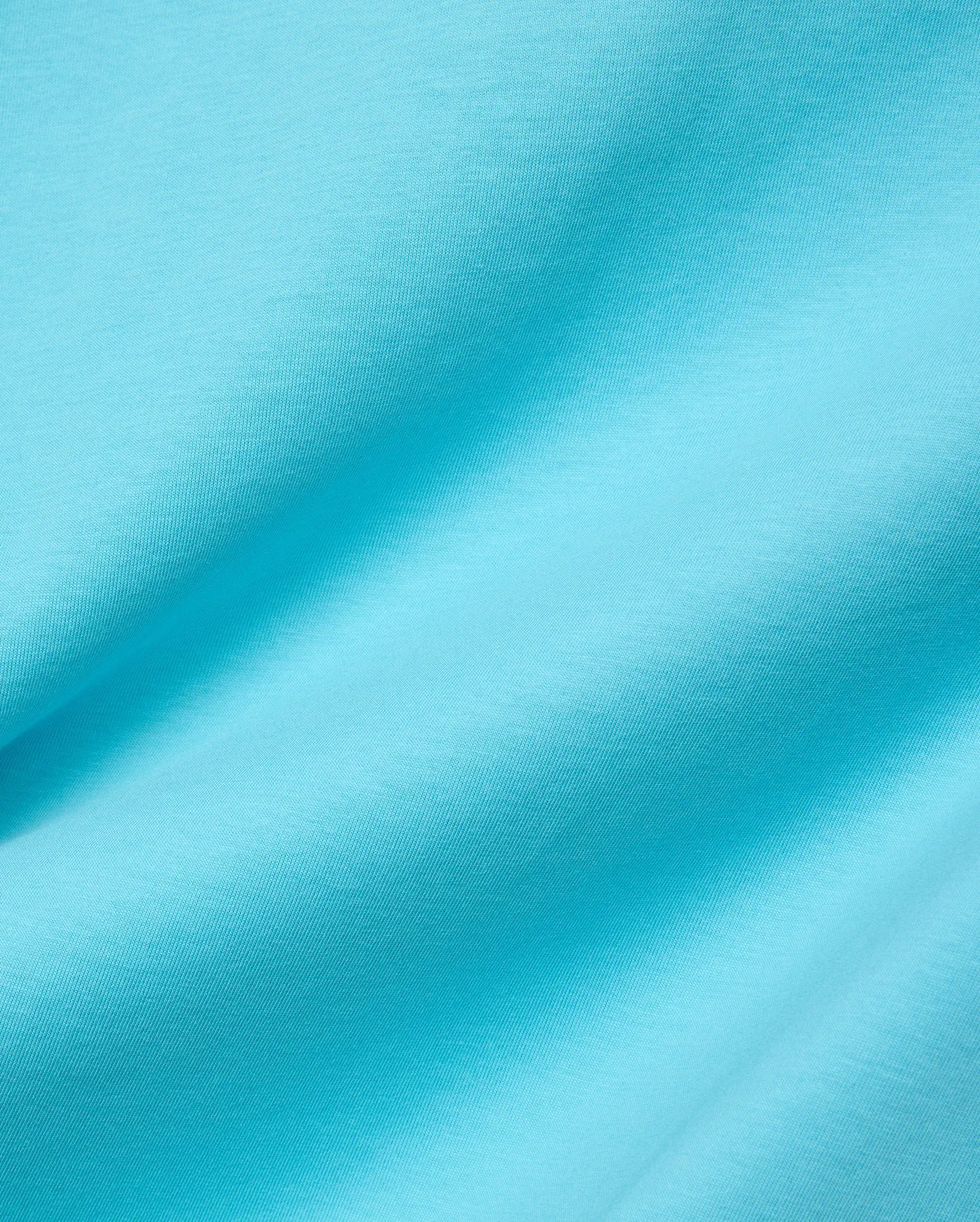 Mens Isaac Relaxed Fit Tee in bright aqua blue, soft jersey knit fabric with visible subtle texture and gentle folds, featuring the iconic small embroidered Psycho Bunny skull logo on the chest.