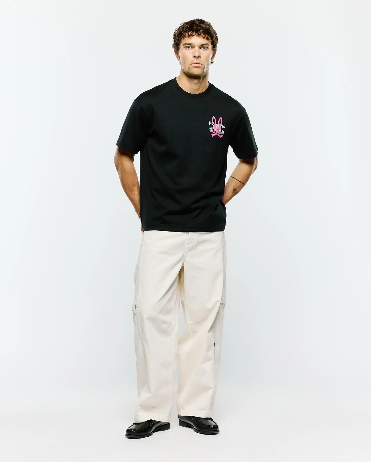 Mens Duncan Relaxed Fit Tee, a black relaxed fit jersey tee featuring a vibrant pink embroidered Psycho Bunny skull logo and text on the left chest.