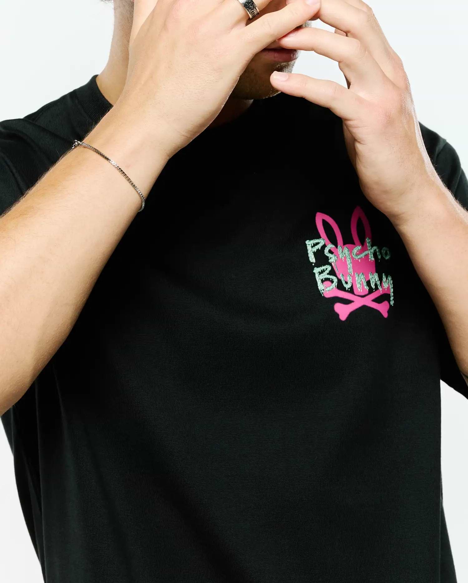 MENS DUNCAN RELAXED FIT TEE, a black jersey knit t-shirt featuring a large, distressed light green Psycho Bunny text graphic over a solid pink bunny skull and crossbones logo on the chest.