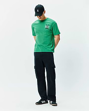 Mens Duncan Relaxed Fit Tee. Vibrant green jersey t-shirt with a relaxed fit, featuring a white embroidered Psycho Bunny skull logo and text on the left chest.