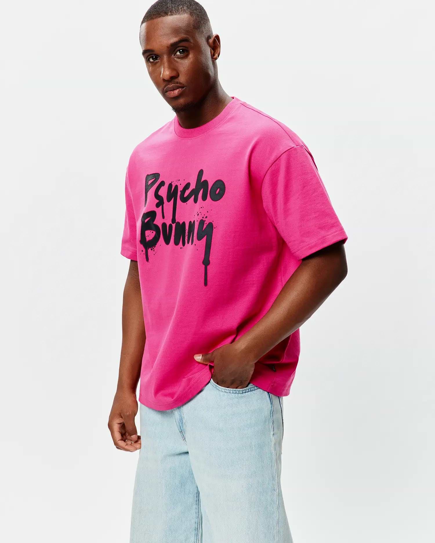Mens Duncan Wordmark Relaxed Fit Tee in vibrant hot pink jersey knit, featuring a large, central black graffiti-style Psycho Bunny wordmark graphic with drip and splatter details, designed for a relaxed fit.