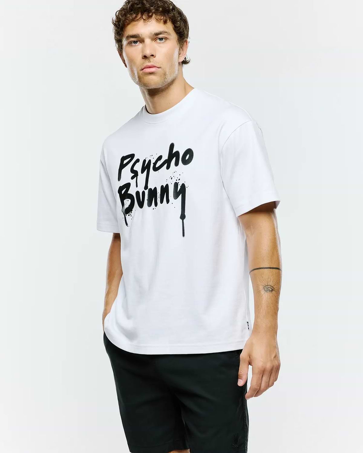 Mens Duncan Wordmark Relaxed Fit Tee, a crisp white cotton jersey t-shirt with a bold, large black spray paint drip effect Psycho Bunny wordmark graphic centered on the chest.