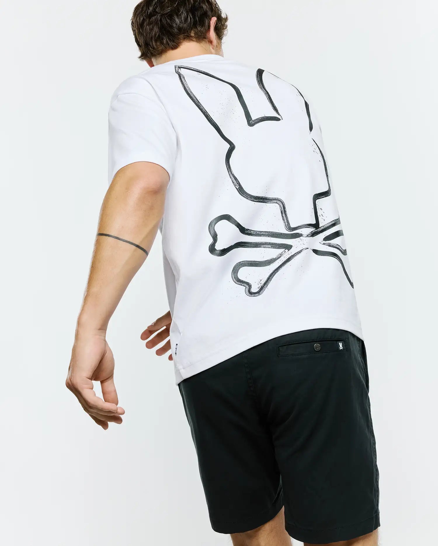 White Mens Duncan Wordmark Relaxed Fit Tee in soft jersey fabric, featuring a large, distressed black Psycho Bunny skull logo graphic prominently displayed on the back.