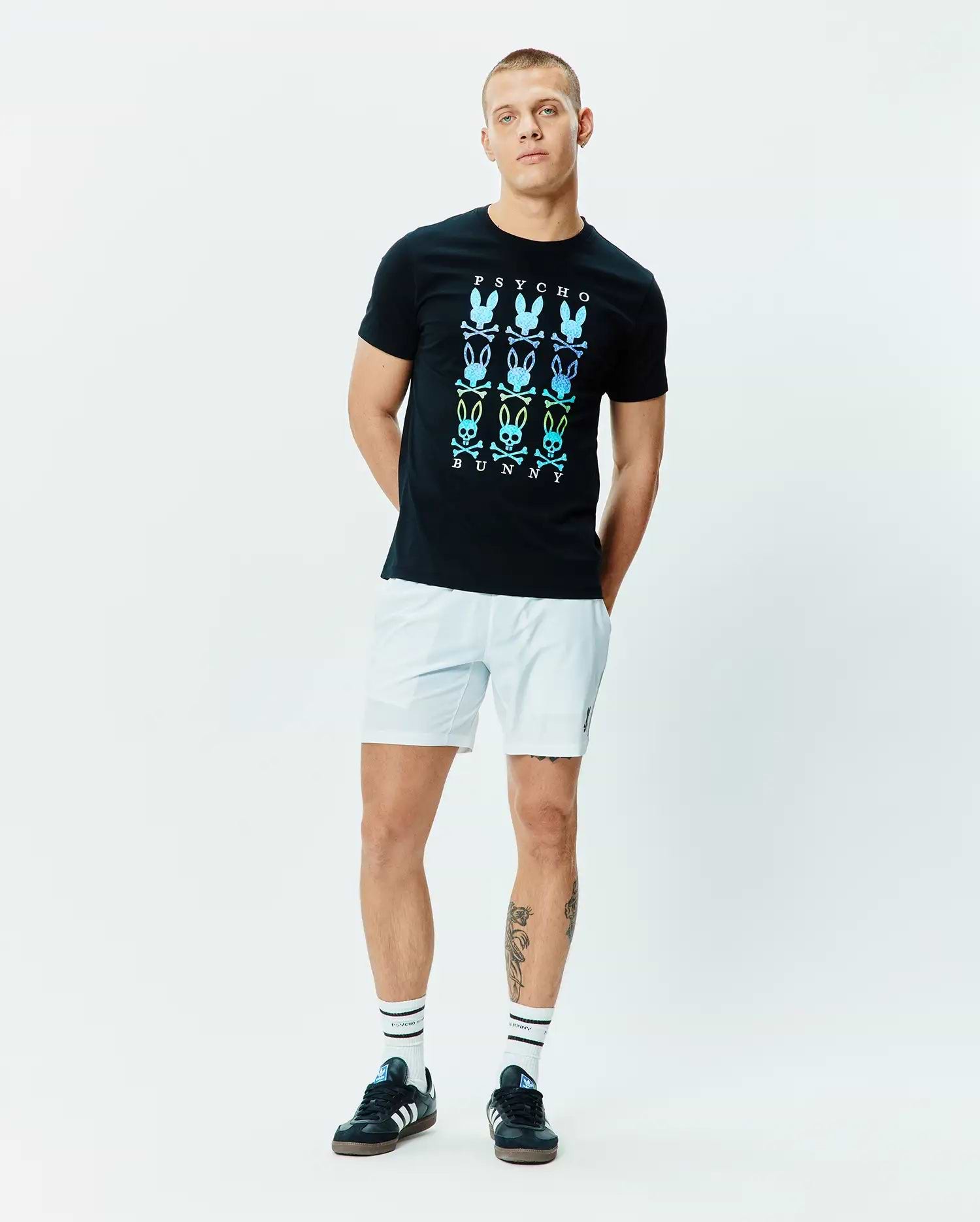Mens Colt Graphic Tee, black, classic fit, smooth jersey knit, featuring a large central chest graphic of nine gradient blue, green, yellow Psycho Bunny skull logos with PSYCHO and BUNNY text. (5)