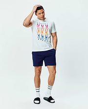 White Mens Colt Graphic Tee, classic fit jersey, featuring a large multi-color gradient Psycho Bunny skull logo graphic on the chest, paired with navy blue smooth athletic shorts with a small white embroidered bunny logo. (5)
