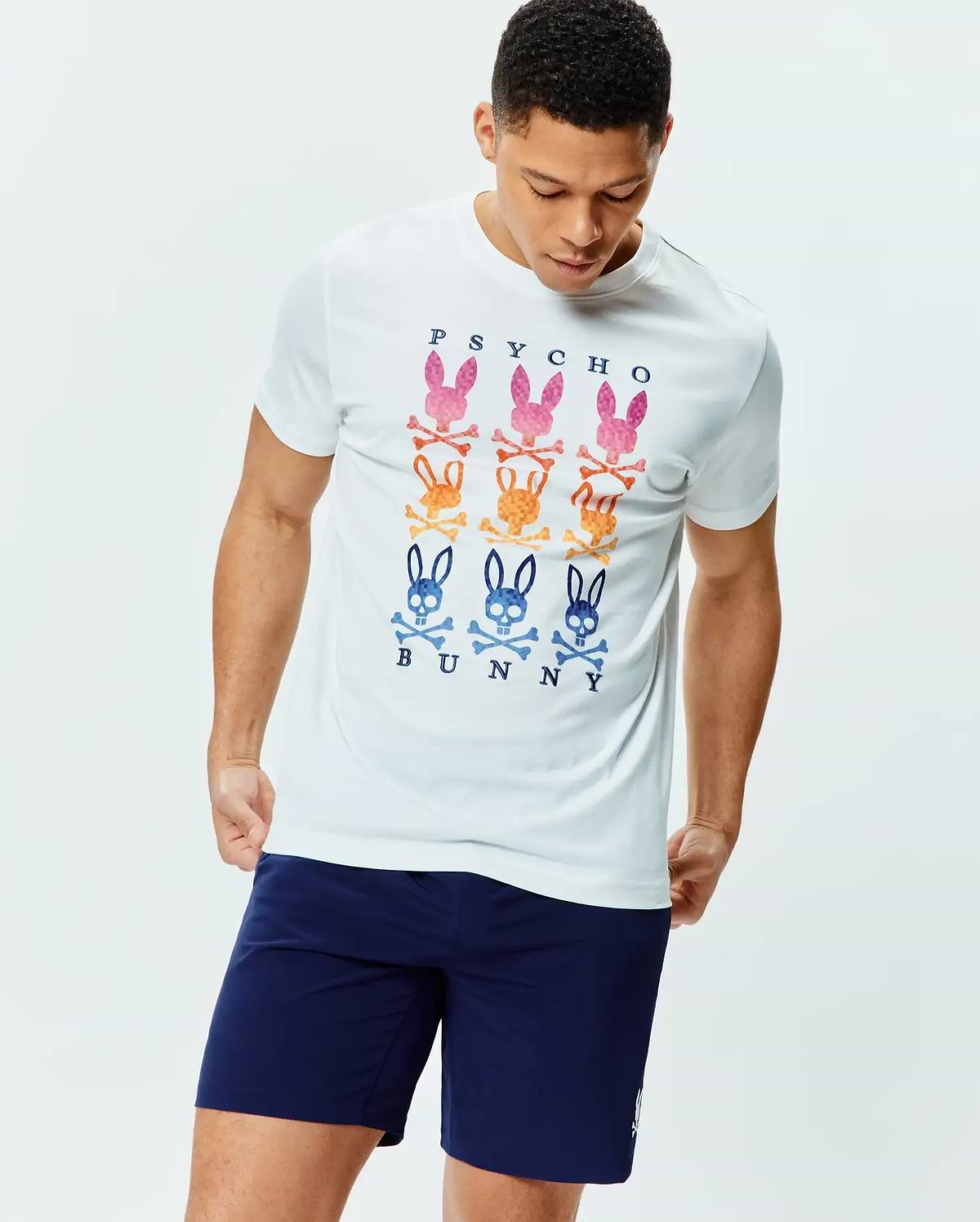 Mens Colt Graphic Tee. White classic fit jersey t-shirt with a large chest graphic featuring nine colorful Psycho Bunny skull and crossbones logos in pink, orange, and blue, with navy PSYCHO BUNNY text. (2)
