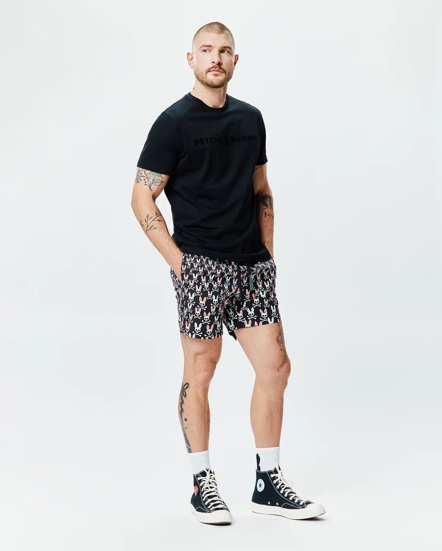 Black Mens Royce Graphic Tee, classic fit, soft jersey, featuring a tonal Psycho Bunny chest graphic, paired with black relaxed-fit shorts showcasing an all-over vibrant bunny skull and crossbones print. (4)
