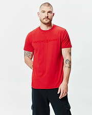 Mens Royce Graphic Tee in vibrant red jersey, featuring a classic fit and a large tonal Psycho Bunny skull logo graphic print centered on the chest.