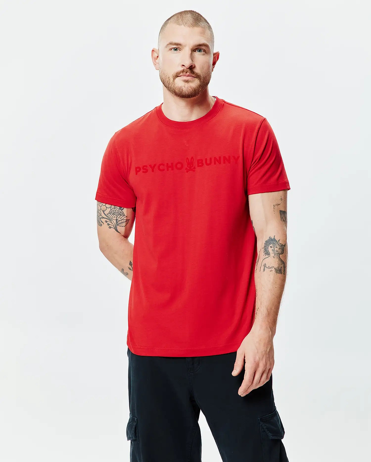 Mens Royce Graphic Tee in vibrant red jersey, featuring a classic fit and a large tonal Psycho Bunny skull logo graphic print centered on the chest.