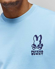 Mens Toby Oversized Tee in light blue jersey knit, featuring a prominent dark blue embroidered Psycho Bunny skull logo with text on the left chest. (2)