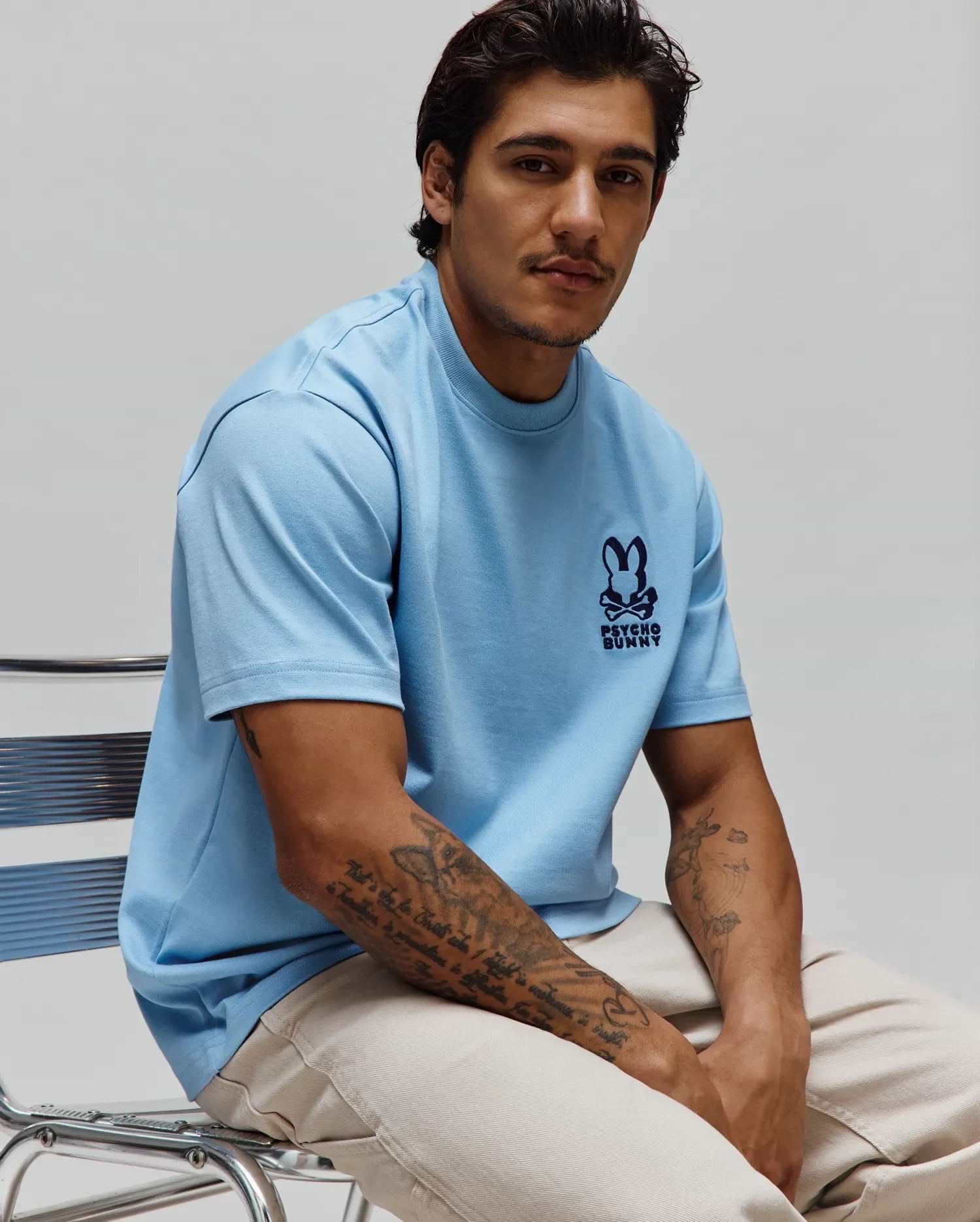 Mens Toby Oversized Tee in light blue, featuring a dark blue embroidered Psycho Bunny skull logo on the left chest. This smooth jersey knit t-shirt offers a relaxed, oversized fit. (1)