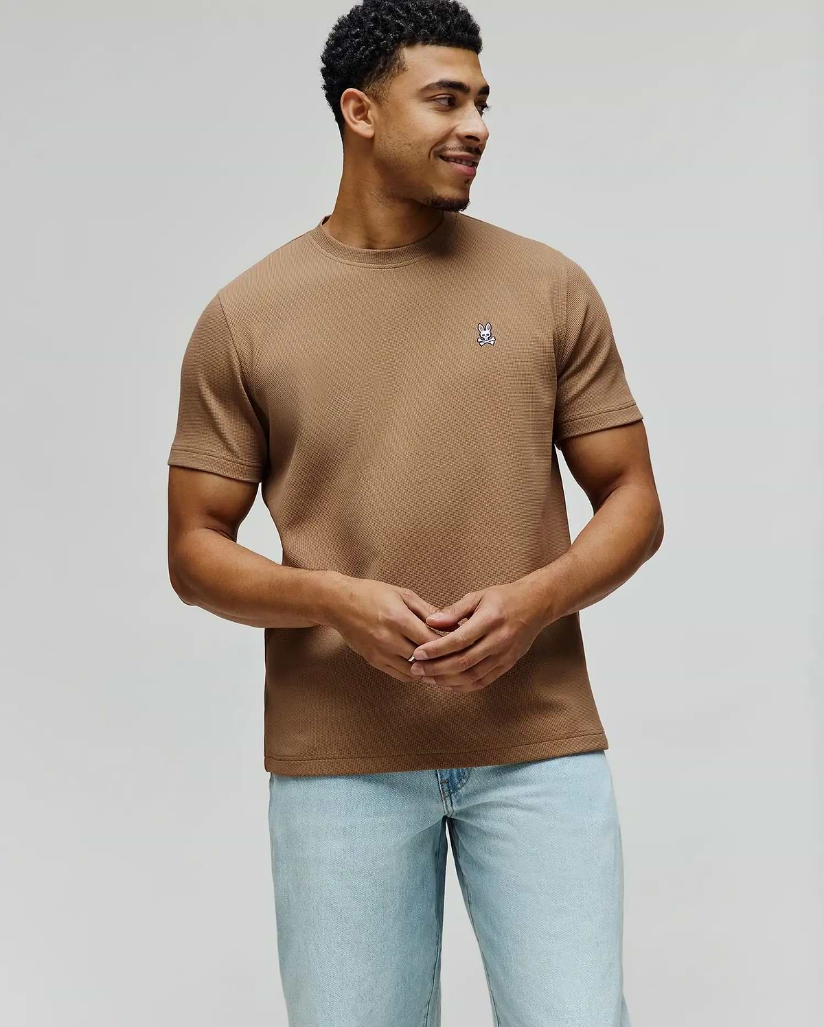 Mens Maxton Waffle Tee in tan, featuring a classic fit and textured waffle knit fabric. A small, embroidered Psycho Bunny skull logo in white, blue, and black adorns the left chest.