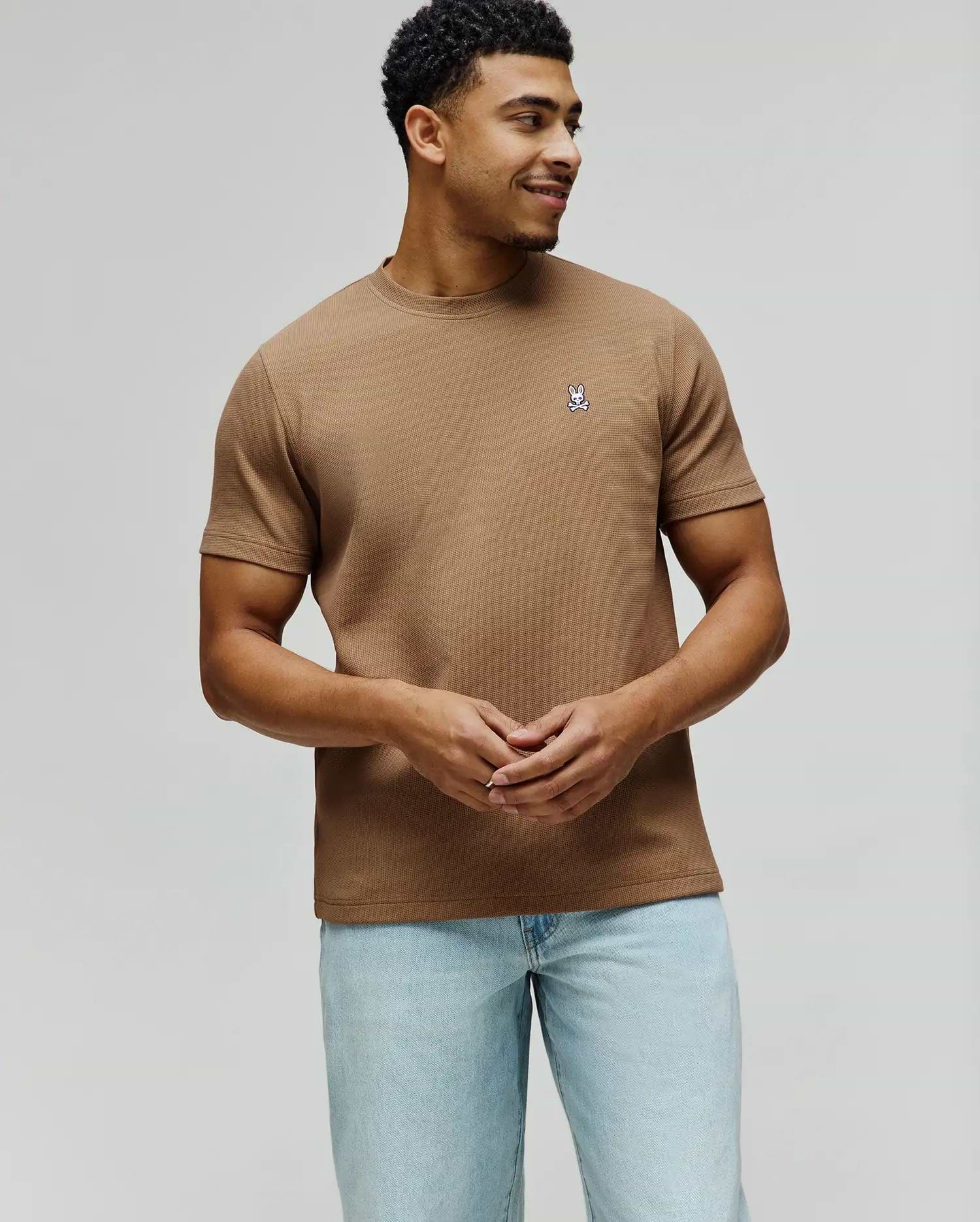 Mens Maxton Waffle Tee in tan, featuring a classic fit and textured waffle knit fabric. A small, embroidered Psycho Bunny skull logo in white, blue, and black adorns the left chest.