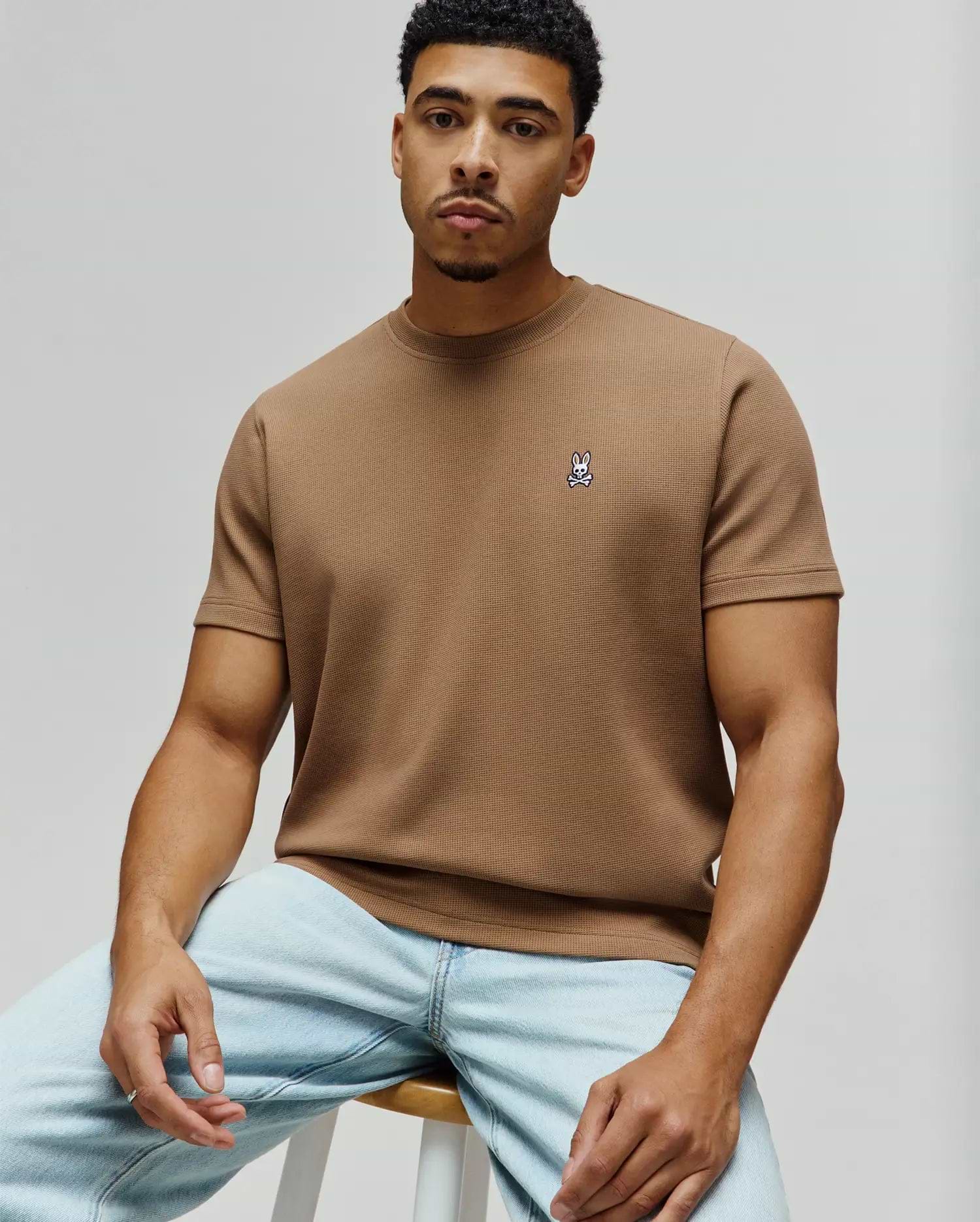 Psycho Bunny Mens Maxton Waffle Tee, a classic fit tan waffle knit t-shirt featuring a small embroidered white and black bunny skull logo on the left chest.