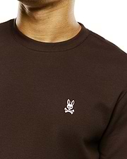 Men's Maxton Waffle Tee, a dark brown classic fit waffle knit long-sleeve t-shirt with a small white embroidered Psycho Bunny skull logo on the left chest. (2)