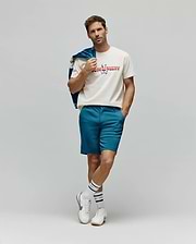 Mens Raphael Wordmark Tee, a classic fit cream jersey t-shirt featuring a large, multicolored patterned Psycho Bunny wordmark and skull logo on the chest, complemented by slim-fit teal shorts. (4)