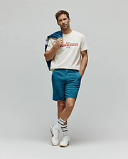 Mens Raphael Wordmark Tee, a classic fit cream jersey t-shirt featuring a large, multicolored patterned Psycho Bunny wordmark and skull logo on the chest, complemented by slim-fit teal shorts. (4)